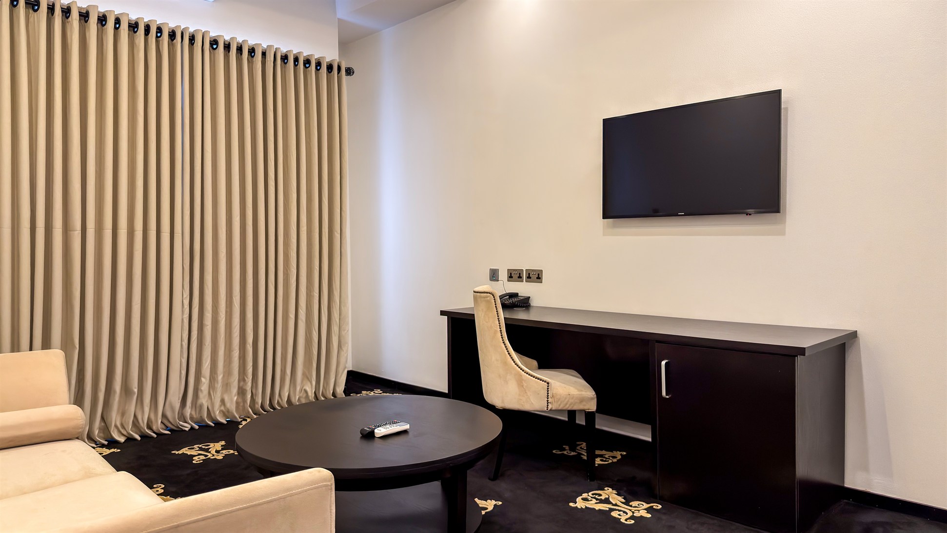 A spacious living room with a work desk and full-height curtains